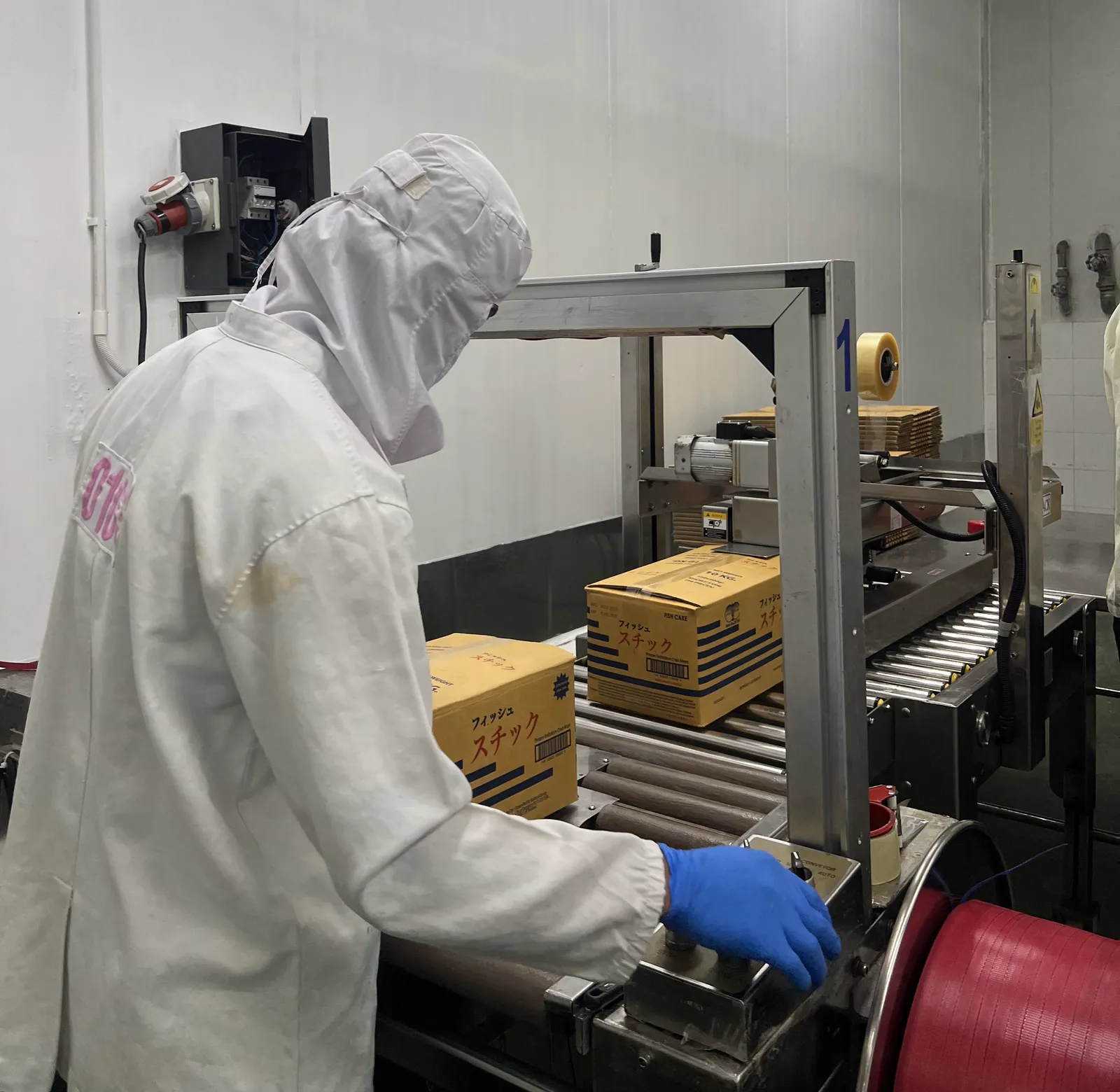A member of the team at the case sealer, boxing cartons of finished product for export.